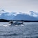A yacht cruising through the ocean with snow covered mountains in the distance